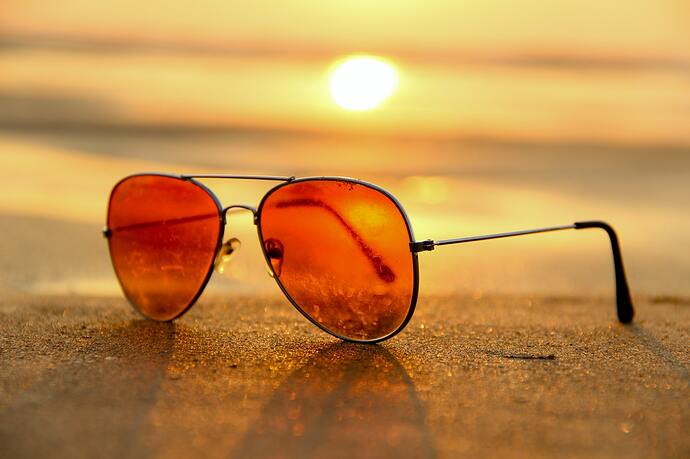 Free Red Lens Sunglasses on Sand Near Sea at Sunset