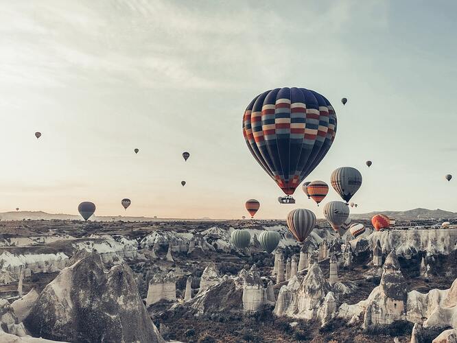 Colorful air balloons flying over picturesque rocky terrain