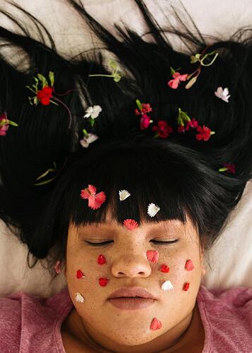 Young woman with flower petals in hair