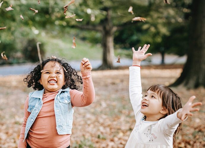 Excited children tossing leaves in park